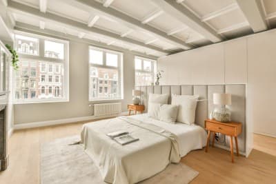 Witte slaapkamer met houten vloer en nachtkastje 